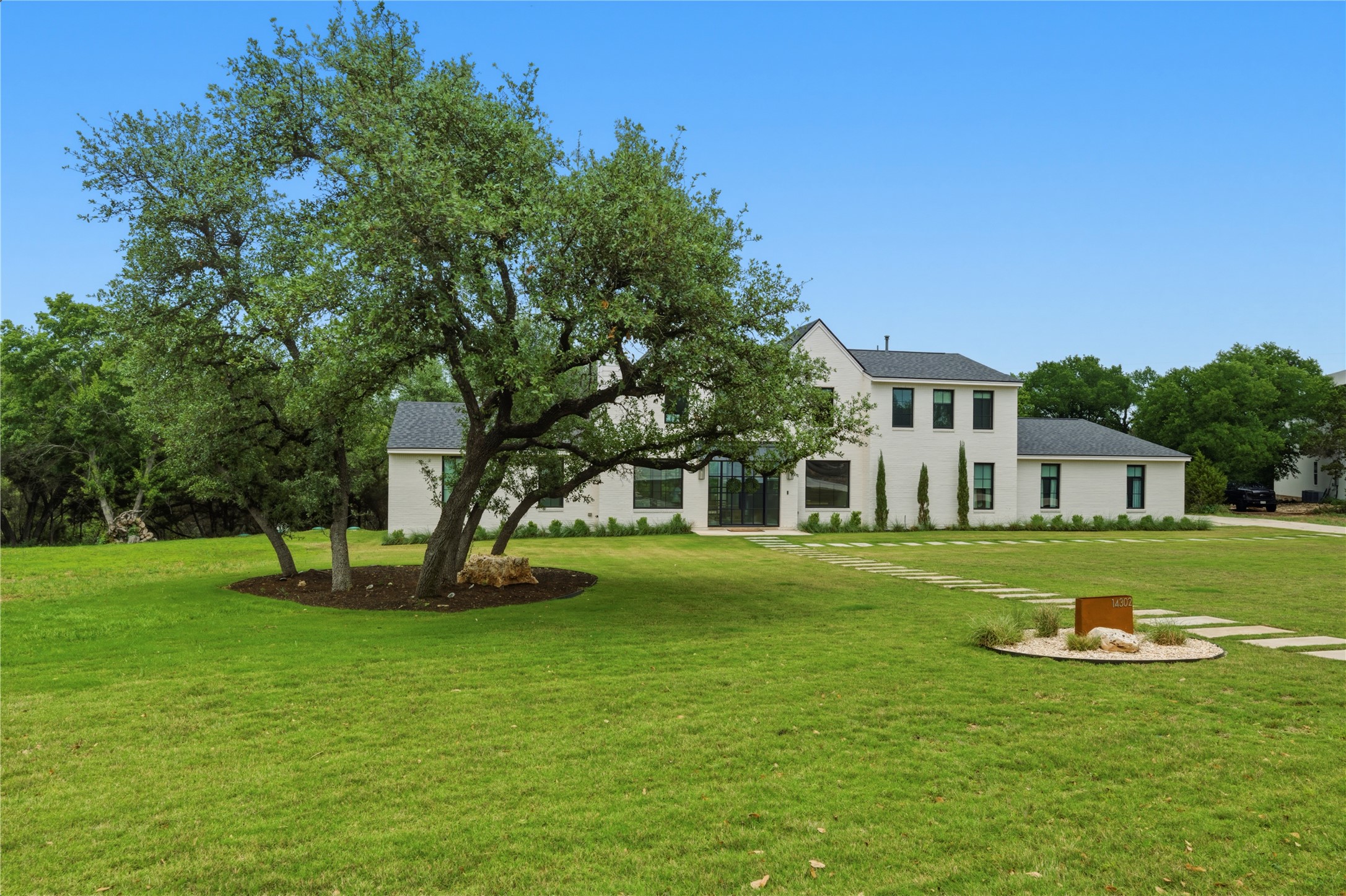 14302 Fallen Timber Drive Austin, TX 78734 - Photo 33 of 37 The property features a white exterior, a dark roof, and a large front yard with mature trees