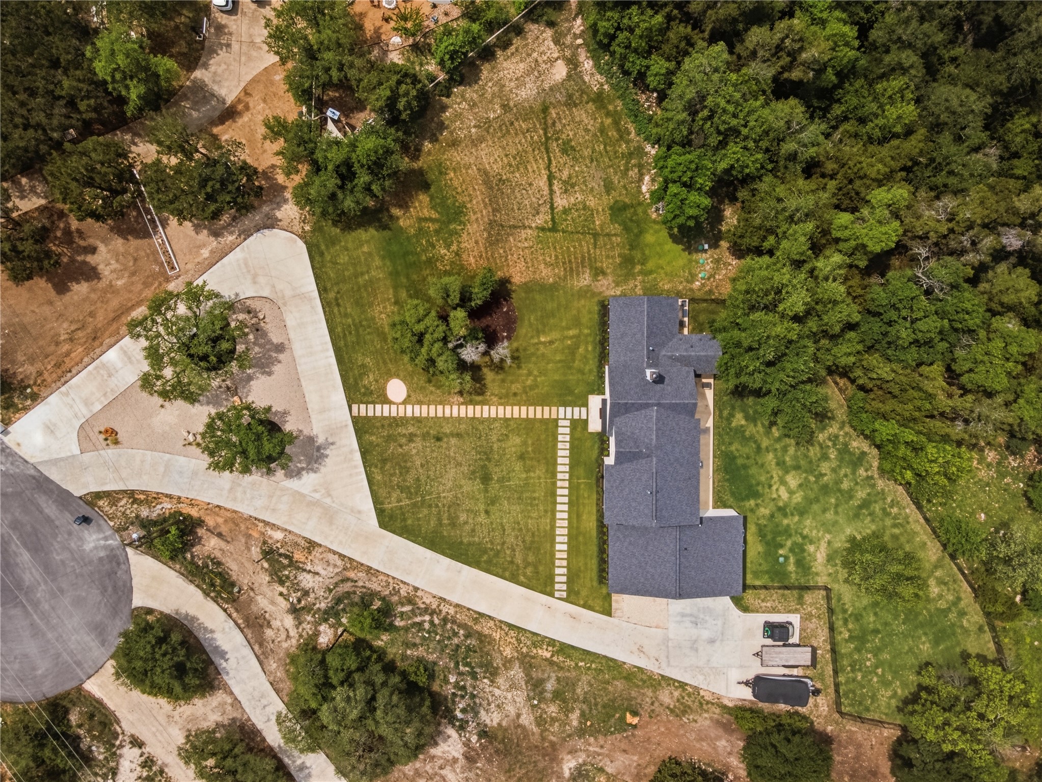 14302 Fallen Timber Drive Austin, TX 78734 - Photo 34 of 37 This property features a contemporary-style residence with a dark-tiled roof, set on an expansive lot with a mix of manicured lawn and natural landscaping