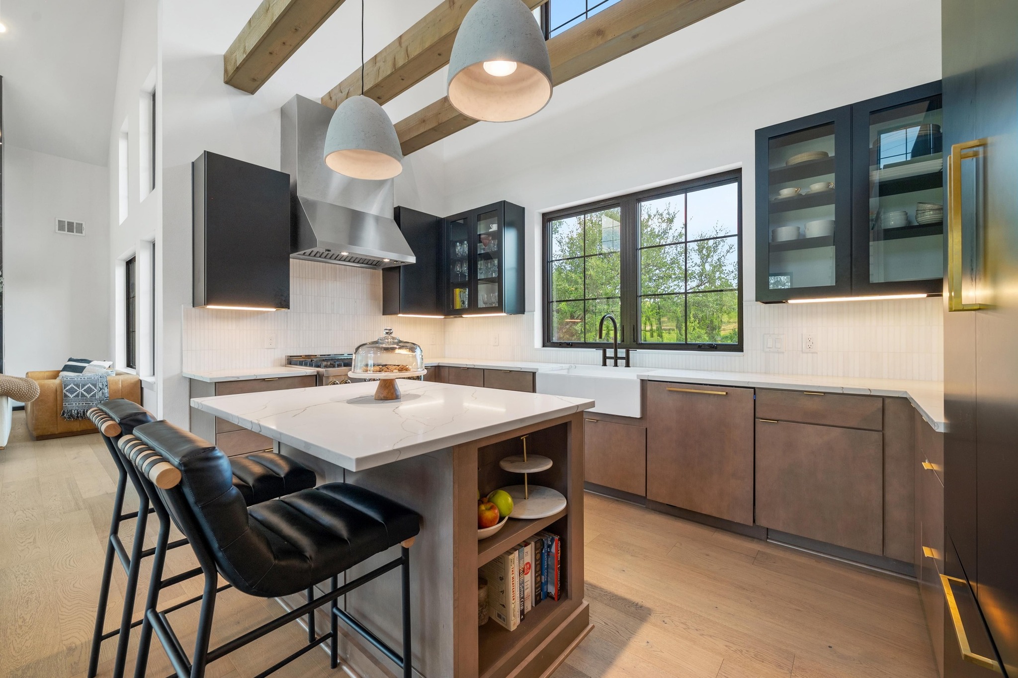 14302 Fallen Timber Drive Austin, TX 78734 - Photo 8 of 37 Modern kitchen featuring an island with a light-colored countertop and seating, wood floors, and exposed beam ceilings