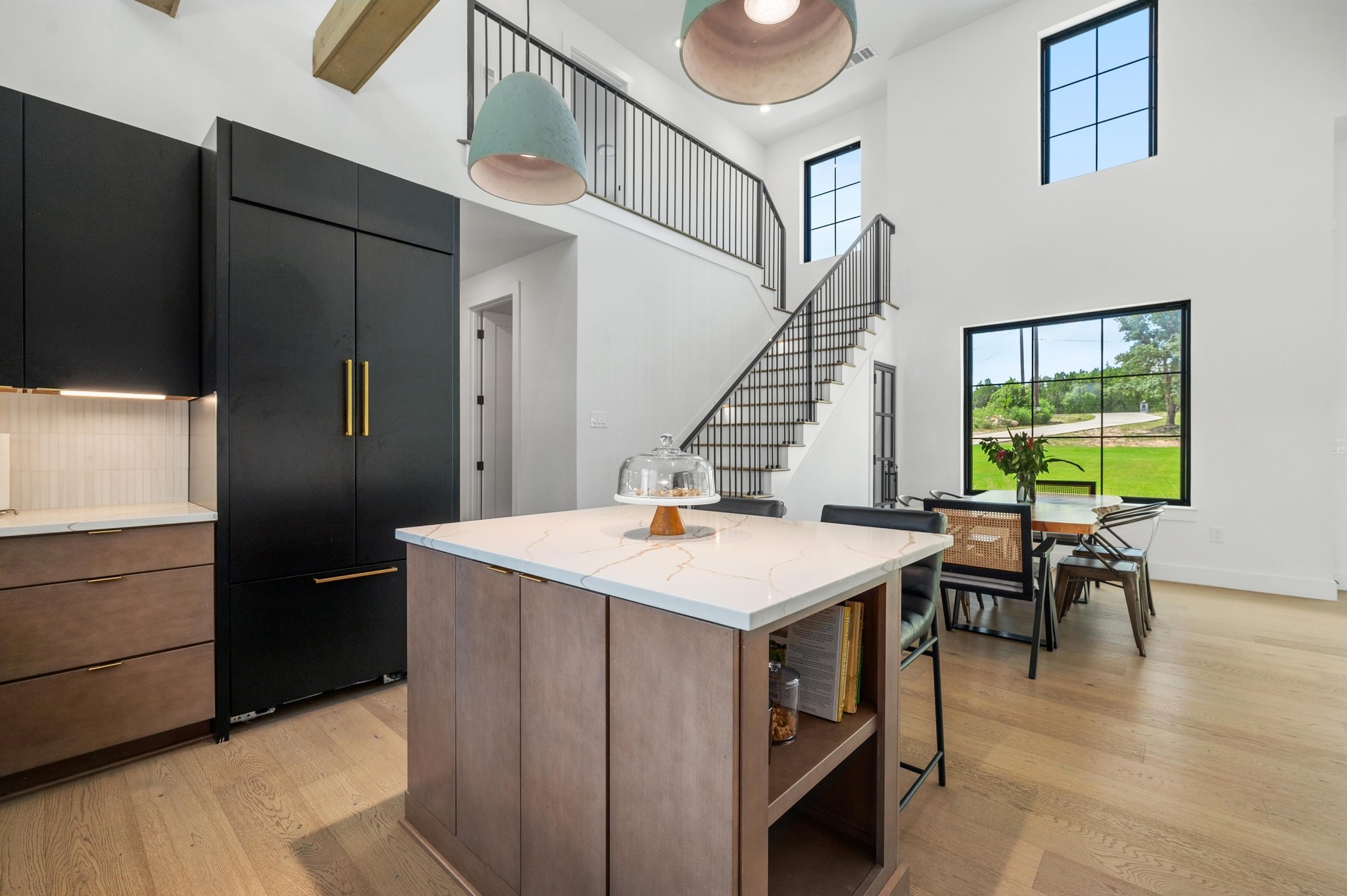 14302 Fallen Timber Drive Austin, TX 78734 - Photo 10 of 37 Modern kitchen with wood floors, a center island featuring a white countertop, and dark cabinetry with gold hardware