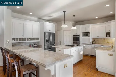 a kitchen with stainless steel appliances granite countertop a stove a sink a refrigerator a center island a table and chairs