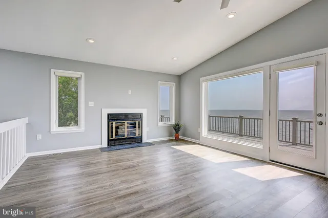 an empty room with floor to ceiling windows and fireplace