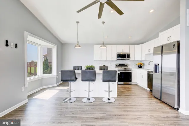 a kitchen with stainless steel appliances kitchen island granite countertop a refrigerator a stove a microwave oven a dining table and chairs with wooden floor