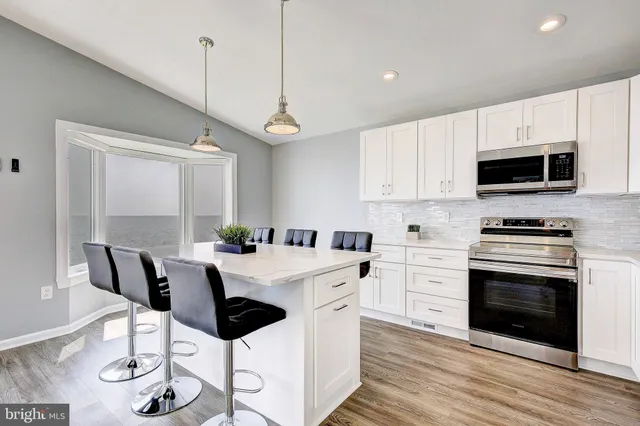 a kitchen with stainless steel appliances a stove a sink island and white cabinets
