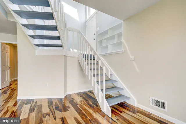 a view of staircase with wooden floor and white walls