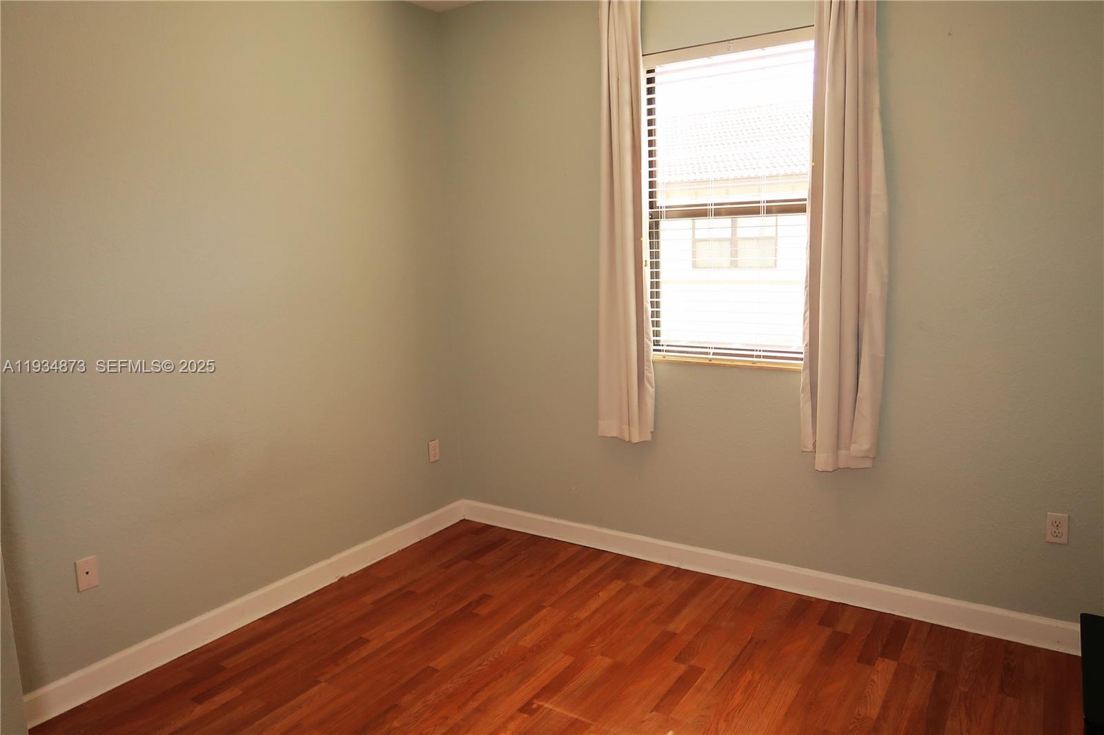 11334 Southwest 236th Street, Unit 11334 Homestead, FL 33032 - Photo 11 of 25 a view of an empty room with wooden floor and a window