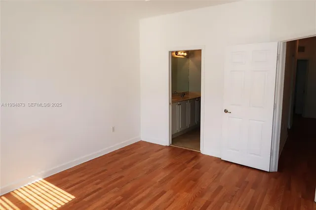 a view of an empty room with wooden floor and closet