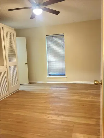 a view of an empty room with window and wooden floor