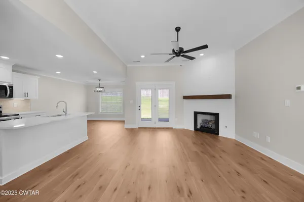 an empty room with wooden floor fireplace and windows