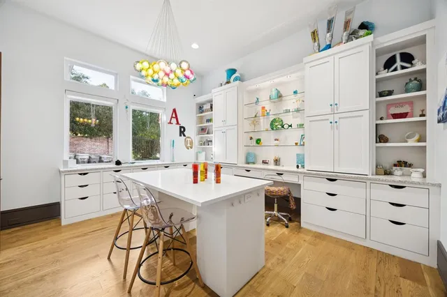 a kitchen that has a lot of white furniture and wooden floor