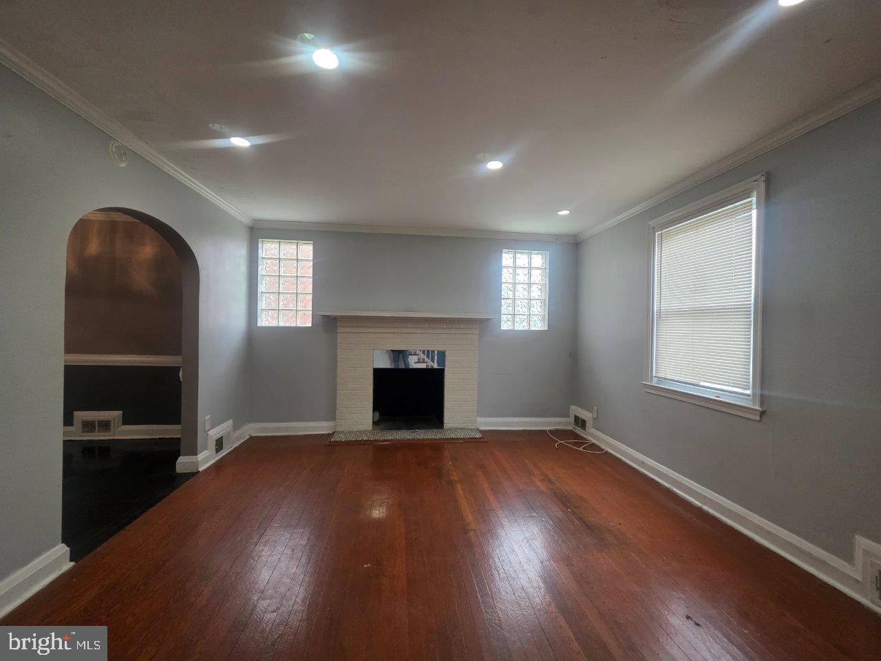 2211 Echodale Avenue Baltimore, MD 21214 - Photo 3 of 30 an empty room with windows fireplace and wooden floor