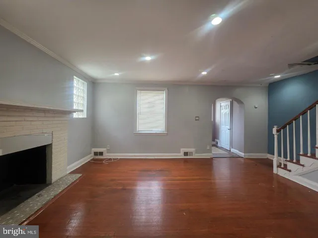 an empty room with wooden floor and fireplace