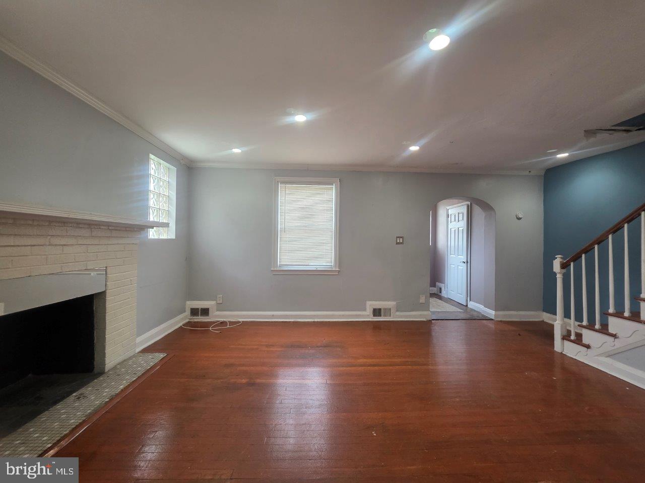 2211 Echodale Avenue Baltimore, MD 21214 - Photo 4 of 30 an empty room with wooden floor and fireplace