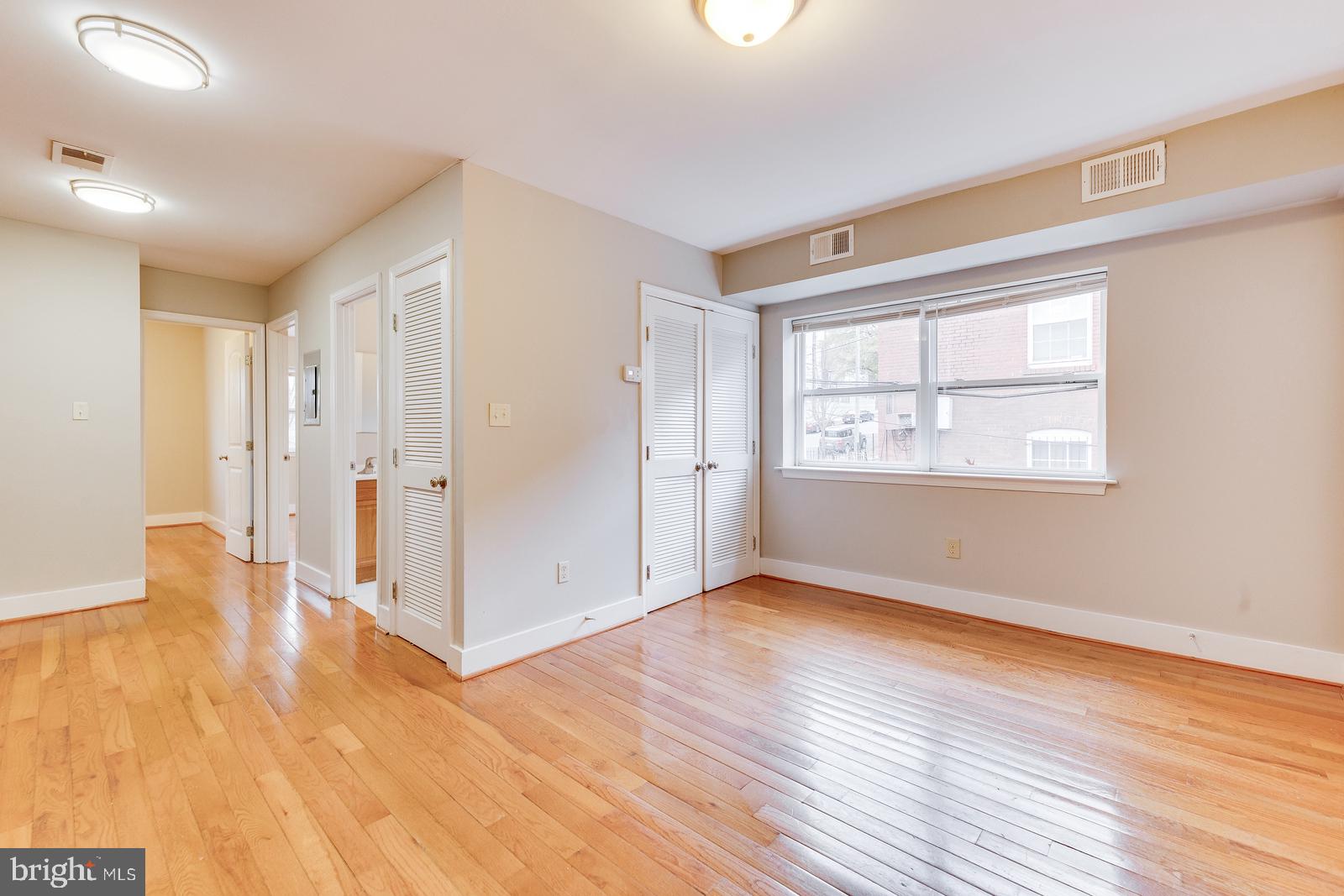 61 Forrester Street Southwest, Unit 104 Washington, DC 20032 - Photo 4 of 13 a view of an empty room with wooden floor and a window