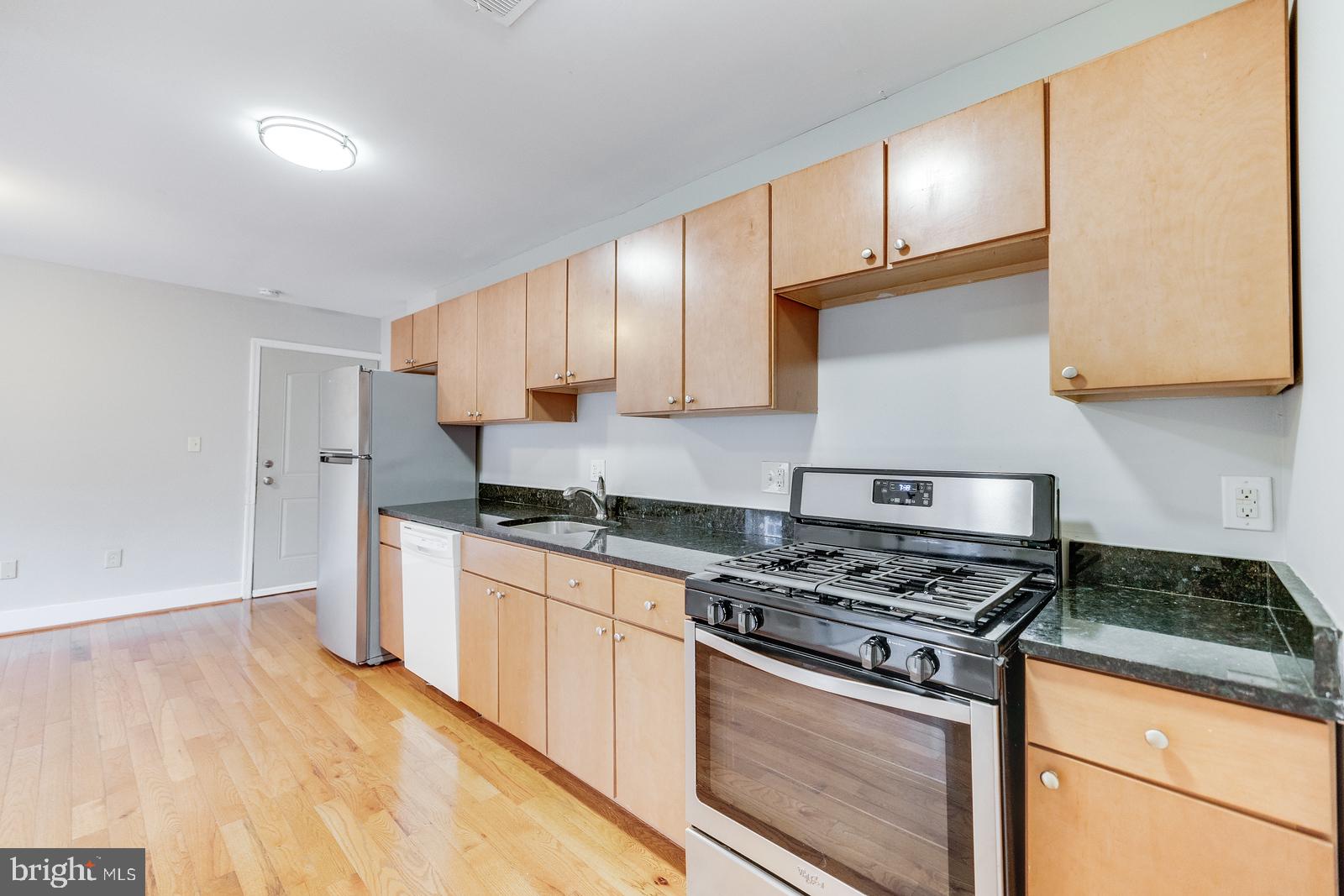 61 Forrester Street Southwest, Unit 104 Washington, DC 20032 - Photo 7 of 13 a kitchen with stainless steel appliances granite countertop a stove a sink and a white cabinets