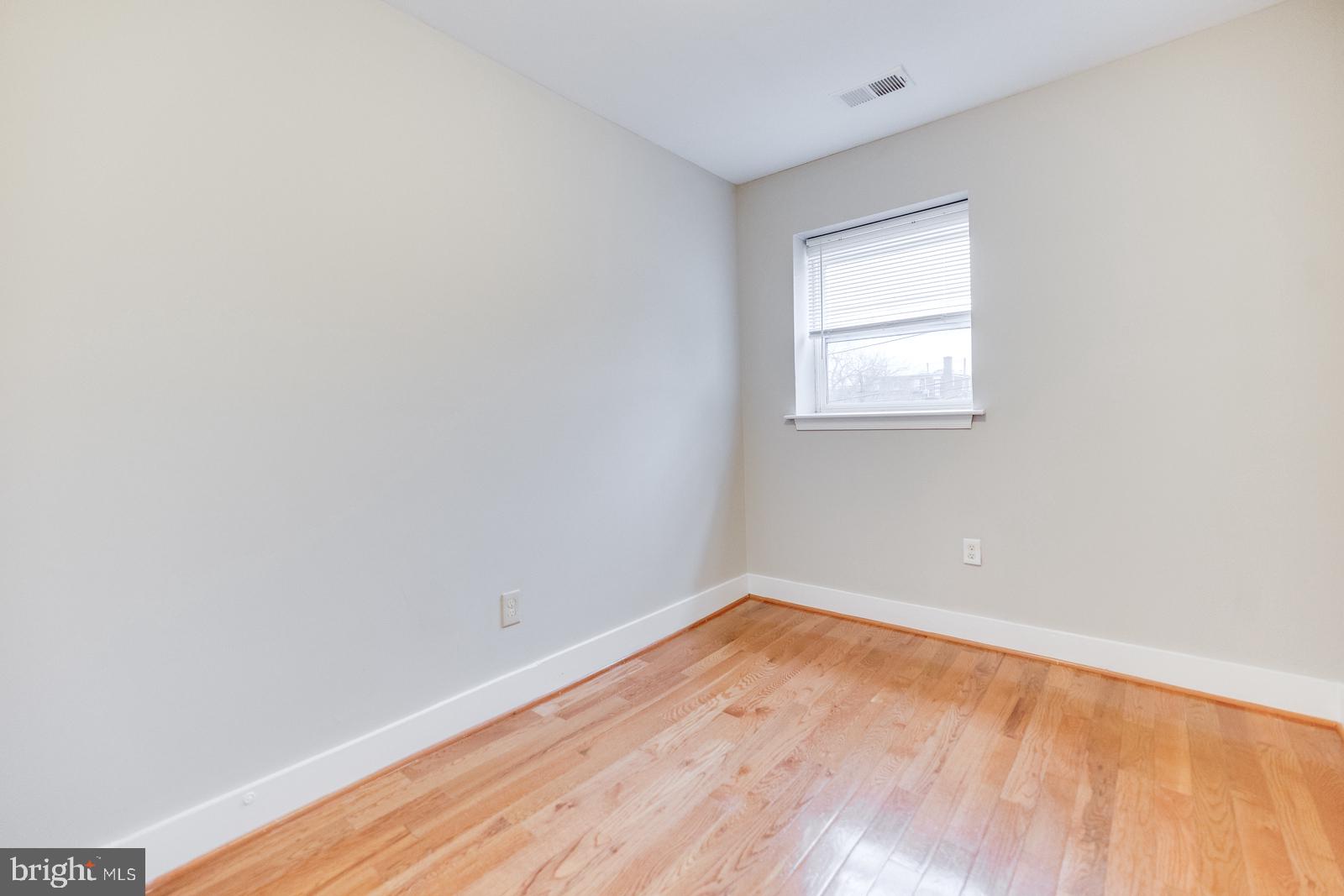 61 Forrester Street Southwest, Unit 104 Washington, DC 20032 - Photo 10 of 13 a view of an empty room with wooden floor and a window