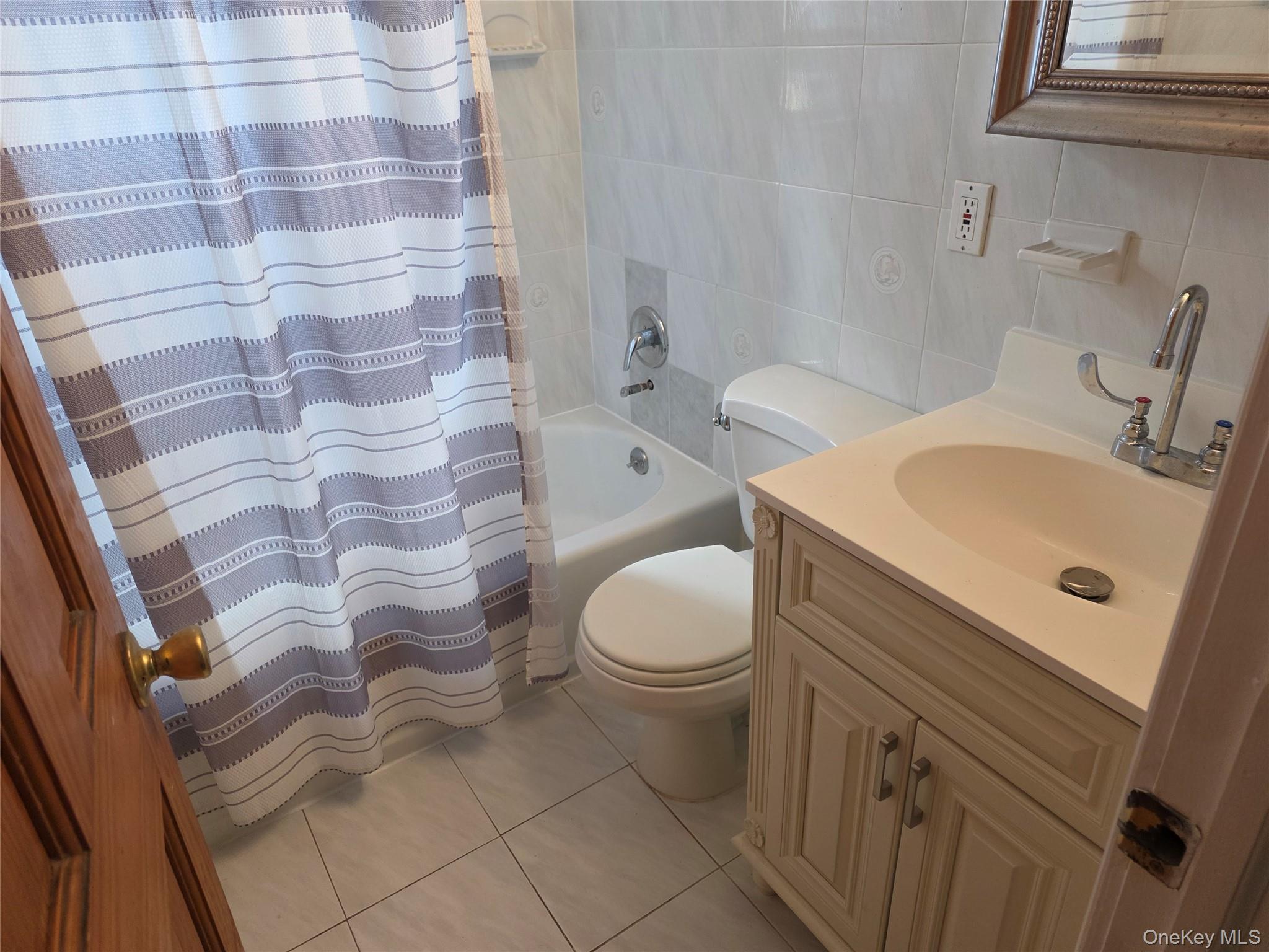 220 Raff Avenue Mineola, NY 11501 - Photo 12 of 22 Full bathroom with tile walls, light tile patterned floors, vanity, and shower / tub combo