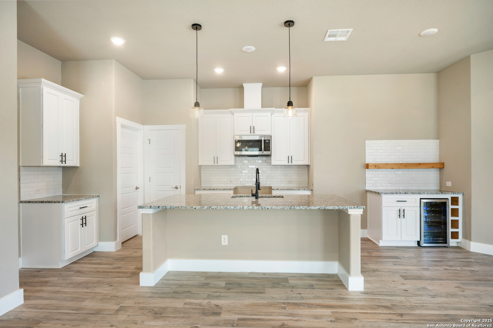 1066 Primrose Path Spring Branch, TX 78070 - Photo 8 of 24 a large kitchen with stainless steel appliances kitchen island granite countertop a refrigerator a stove and white cabinets with wooden floor
