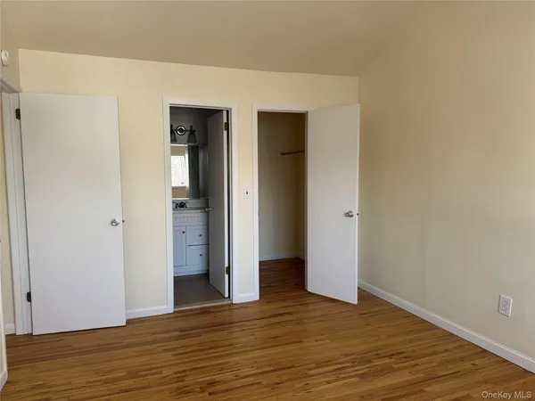a view of an empty room with wooden floor and closet