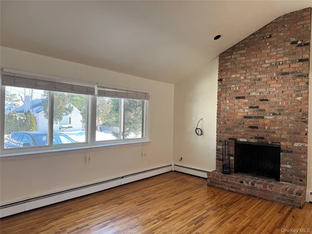 an empty room with wooden floor fireplace and windows