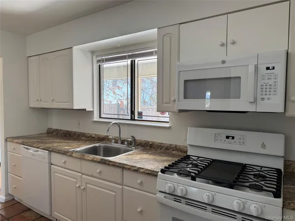 a kitchen with white cabinets and appliances
