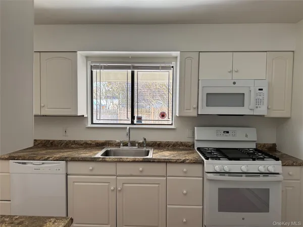 a kitchen with granite countertop white cabinets and a stove