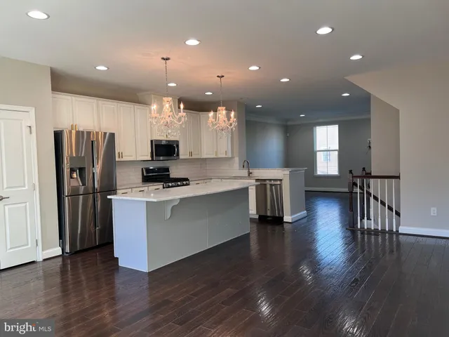 an open kitchen with wooden floor and stainless steel appliances