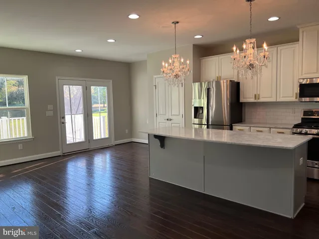 a kitchen with stainless steel appliances kitchen island granite countertop a sink dishwasher a refrigerator and a dining table with wooden floor