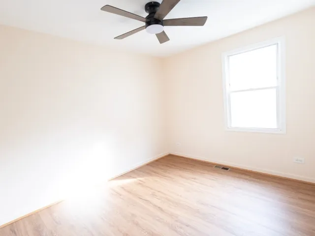 an empty room with a window and a fan