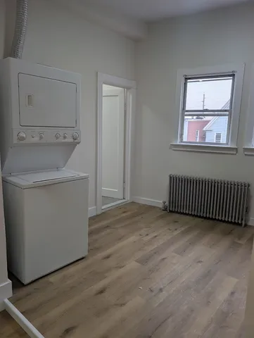 an empty room with wooden floor cabinet and windows