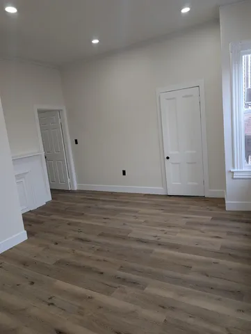 a view of an empty room with wooden floor and entryway