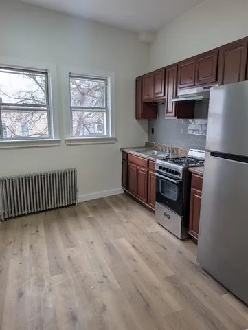 a kitchen with stainless steel appliances granite countertop a stove a refrigerator a sink dishwasher and wooden cabinets with wooden floor