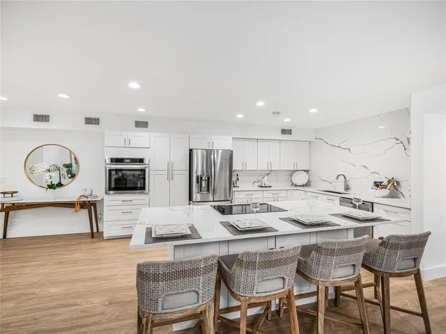 a kitchen with stainless steel appliances granite countertop a table chairs stove and refrigerator