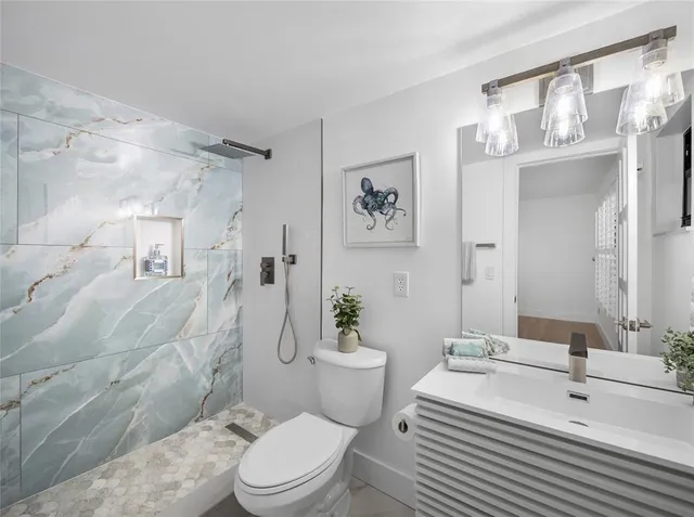 a bathroom with a sink a toilet a mirror and shower