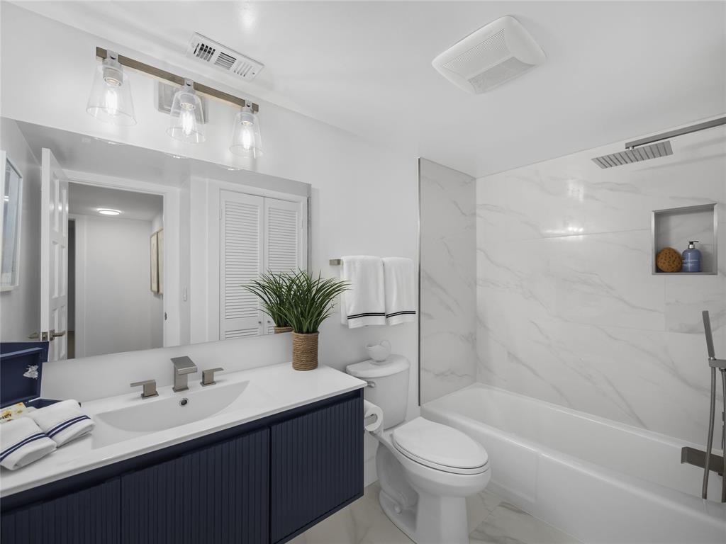 300 North Hwy A1A, Unit 103E Jupiter, FL 33477 - Photo 10 of 12 a bathroom with a double vanity sink toilet and shower