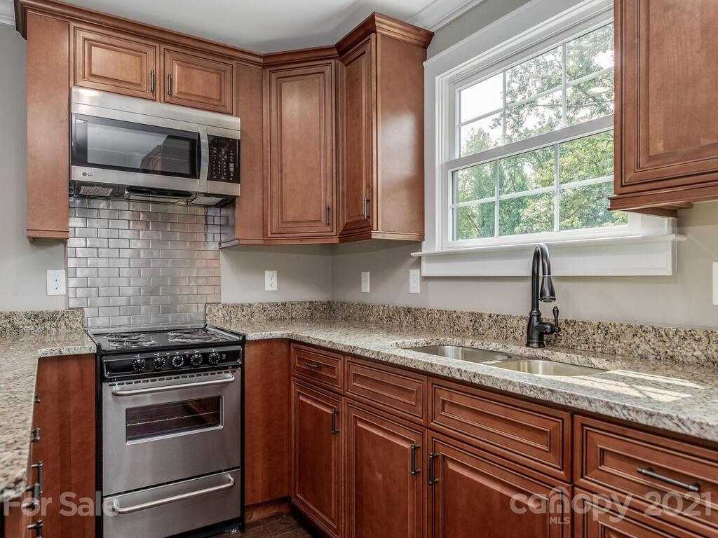 5923 Sharon View Road Charlotte, NC 28226 - Photo 29 of 44 a kitchen with kitchen island granite countertop a sink cabinets stainless steel appliances and a window