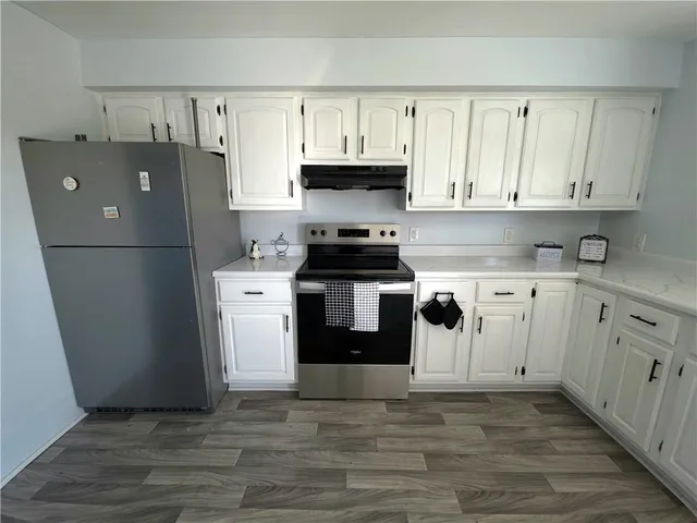 a kitchen with granite countertop white cabinets and white appliances