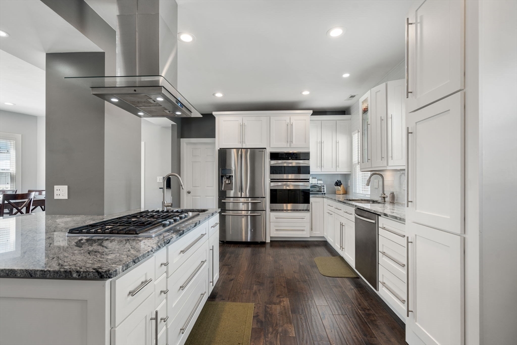 a kitchen with kitchen island granite countertop stainless steel appliances cabinets a sink and a counter top space