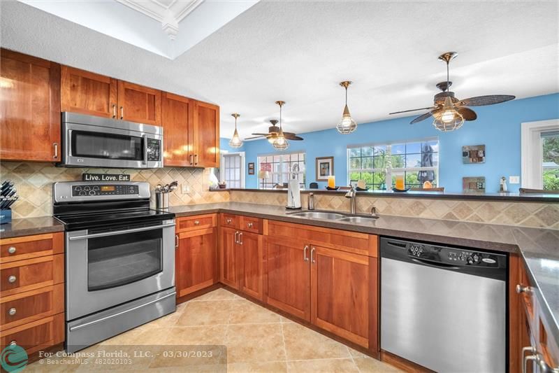 5206 Cleveland Street Hollywood, FL 33021 - Photo 39 of 49 a kitchen with stainless steel appliances granite countertop a stove a sink and a microwave