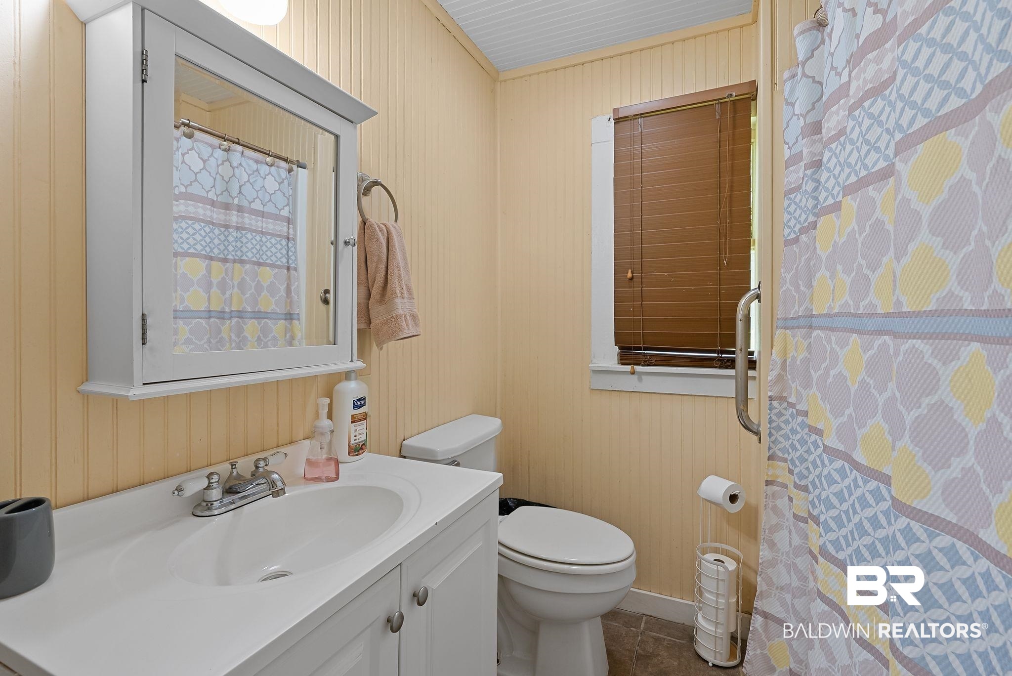 615 West Section Avenue Foley, AL 36535 - Photo 20 of 40 Bathroom featuring beadboard walls, a white vanity with an integrated sink, a mirrored medicine cabinet, a toilet, and a window with horizontal blinds