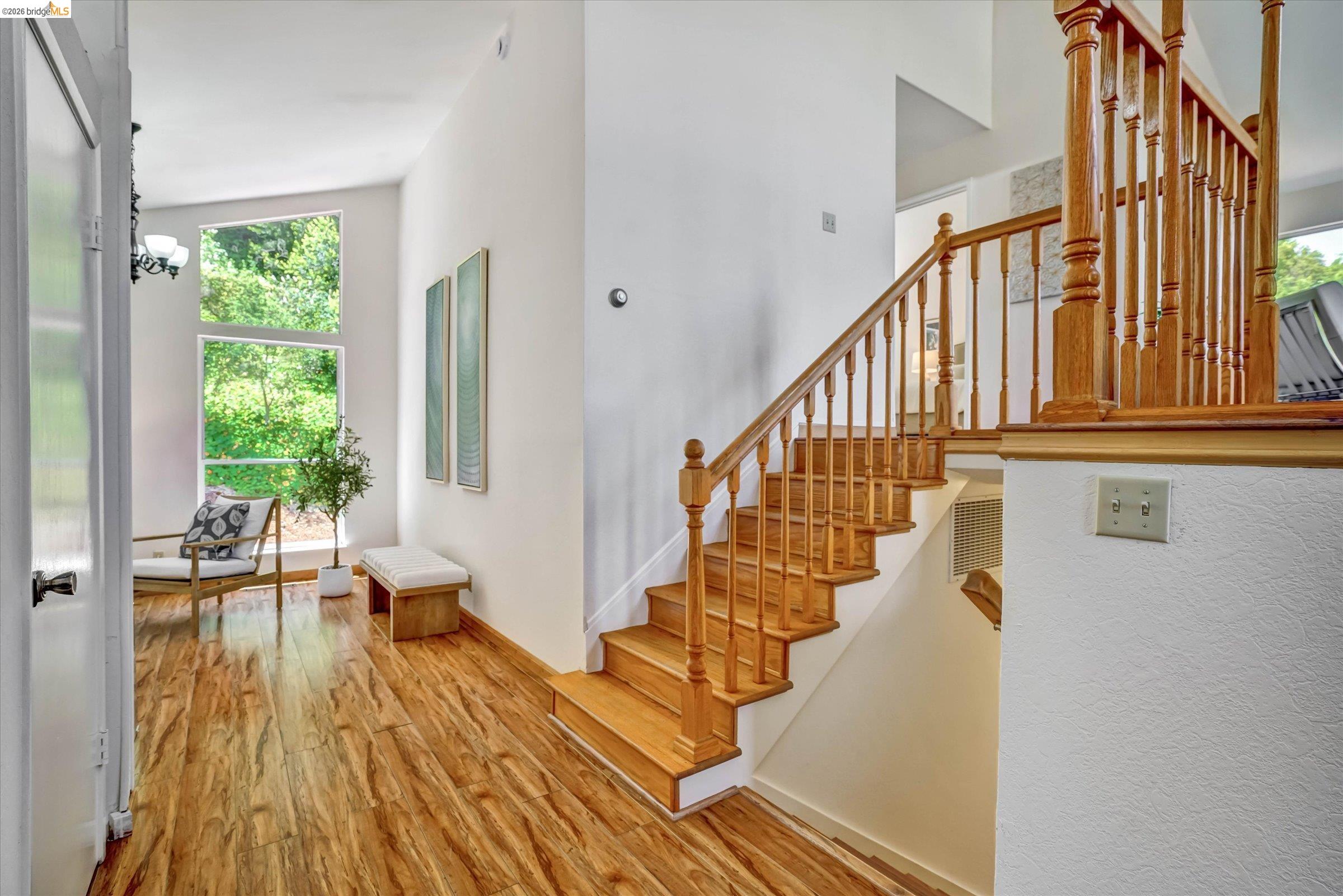 2826 Wright Avenue Pinole, CA 94564 - Photo 9 of 70 Wood-finish flooring throughout a bright interior with a prominent wooden staircase featuring balusters