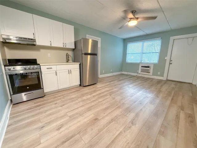 a kitchen with a refrigerator a stove top oven a clock and cabinets
