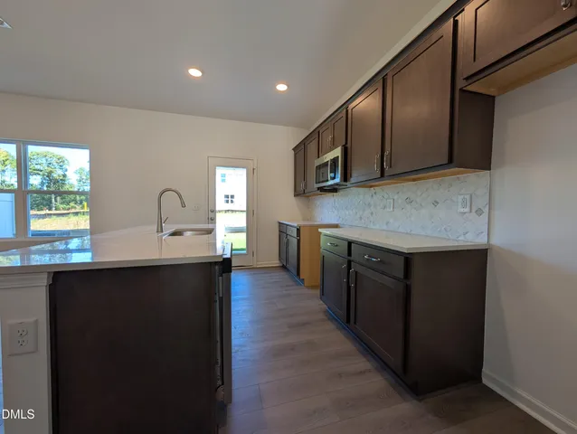 a kitchen with stainless steel appliances granite countertop a sink a stove top oven and wooden cabinets