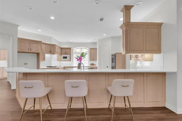 a kitchen with stainless steel appliances granite countertop a table chairs in it and wooden floors