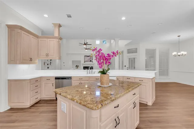 a kitchen with granite countertop kitchen island stainless steel appliances a sink cabinets and wooden floor