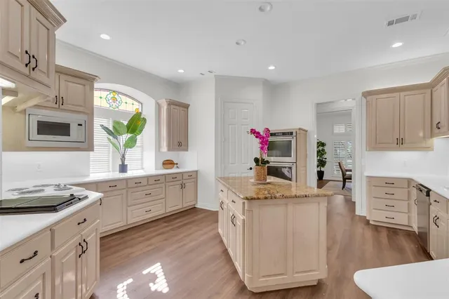 a kitchen with white cabinets and wooden floors