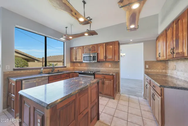 a kitchen with stainless steel appliances granite countertop a sink a stove and a microwave