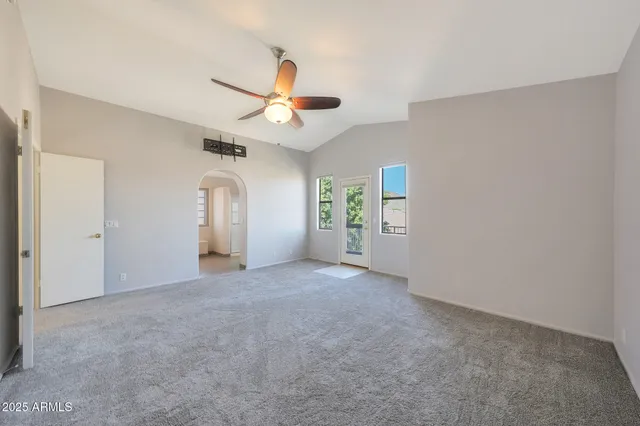 an empty room with windows and fan