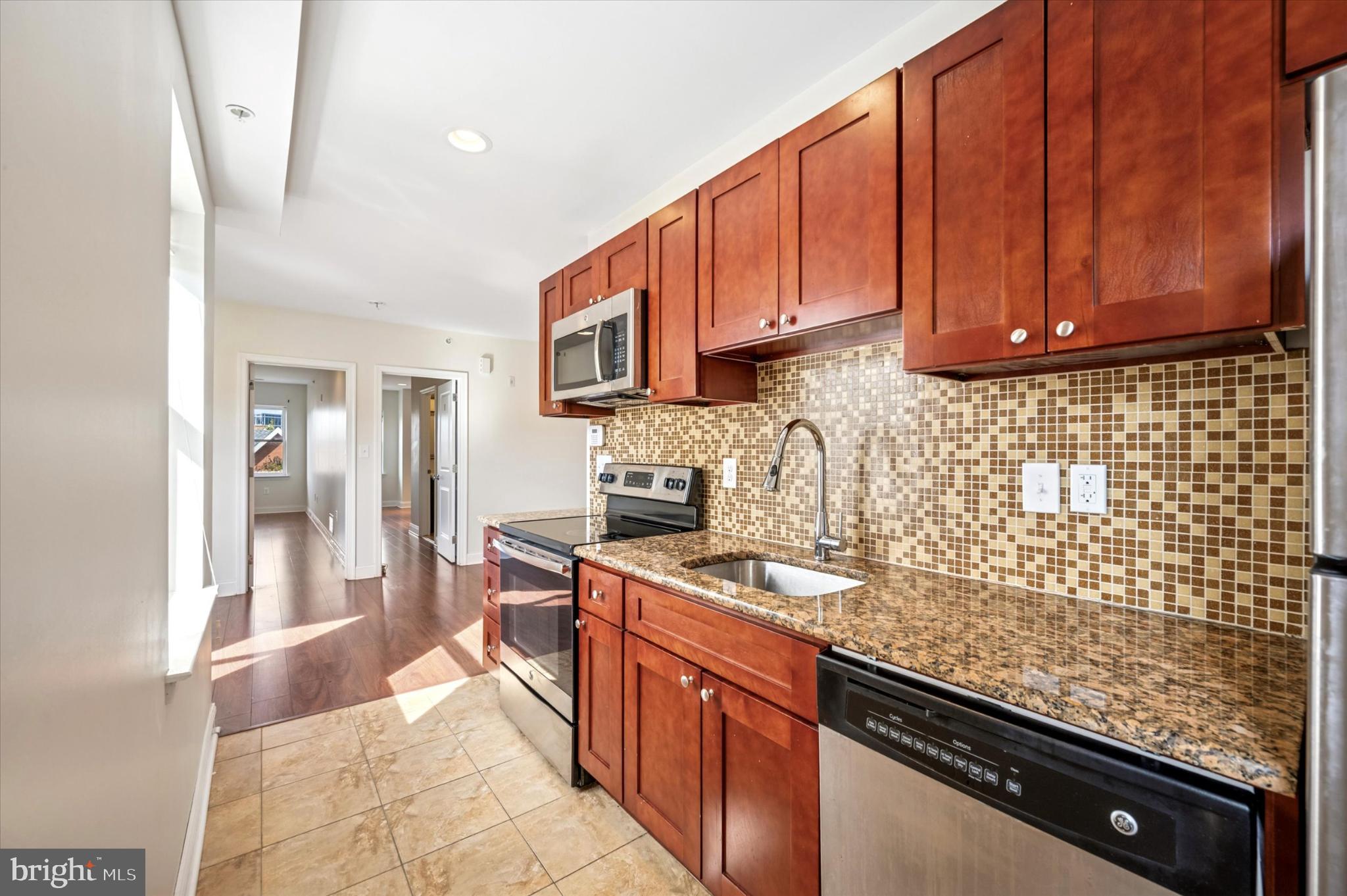 a kitchen with stainless steel appliances granite countertop a sink stove and cabinets