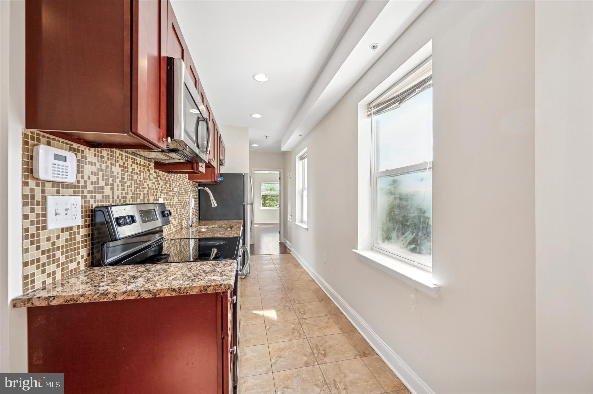 1421 North 18th Street, Unit 3 Philadelphia, PA 19121 - Photo 7 of 16 a kitchen view with granite countertop a stove a sink and a microwave